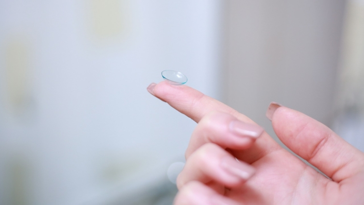 A Contact Lens resting on an index finger
