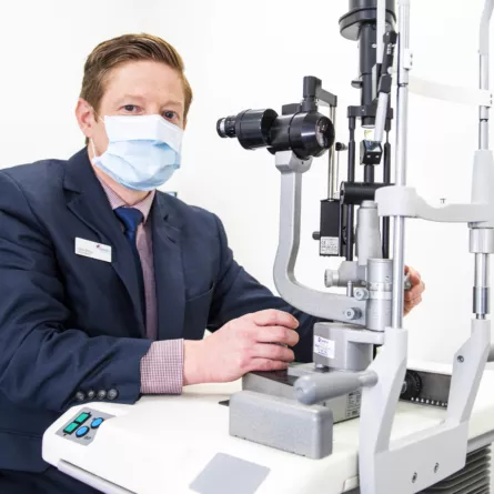 Optegra eye specialist wearing a mask in front of site equipment