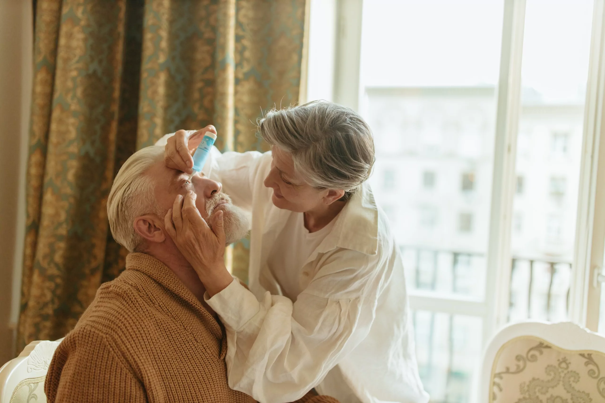 Woman applies eye drops to mans eye